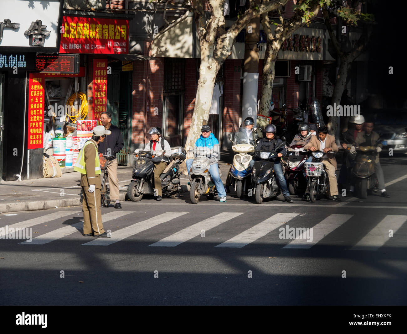 El pueblo chino en scooters esperando la policía para hacerles a través, Shanghai, China Foto de stock