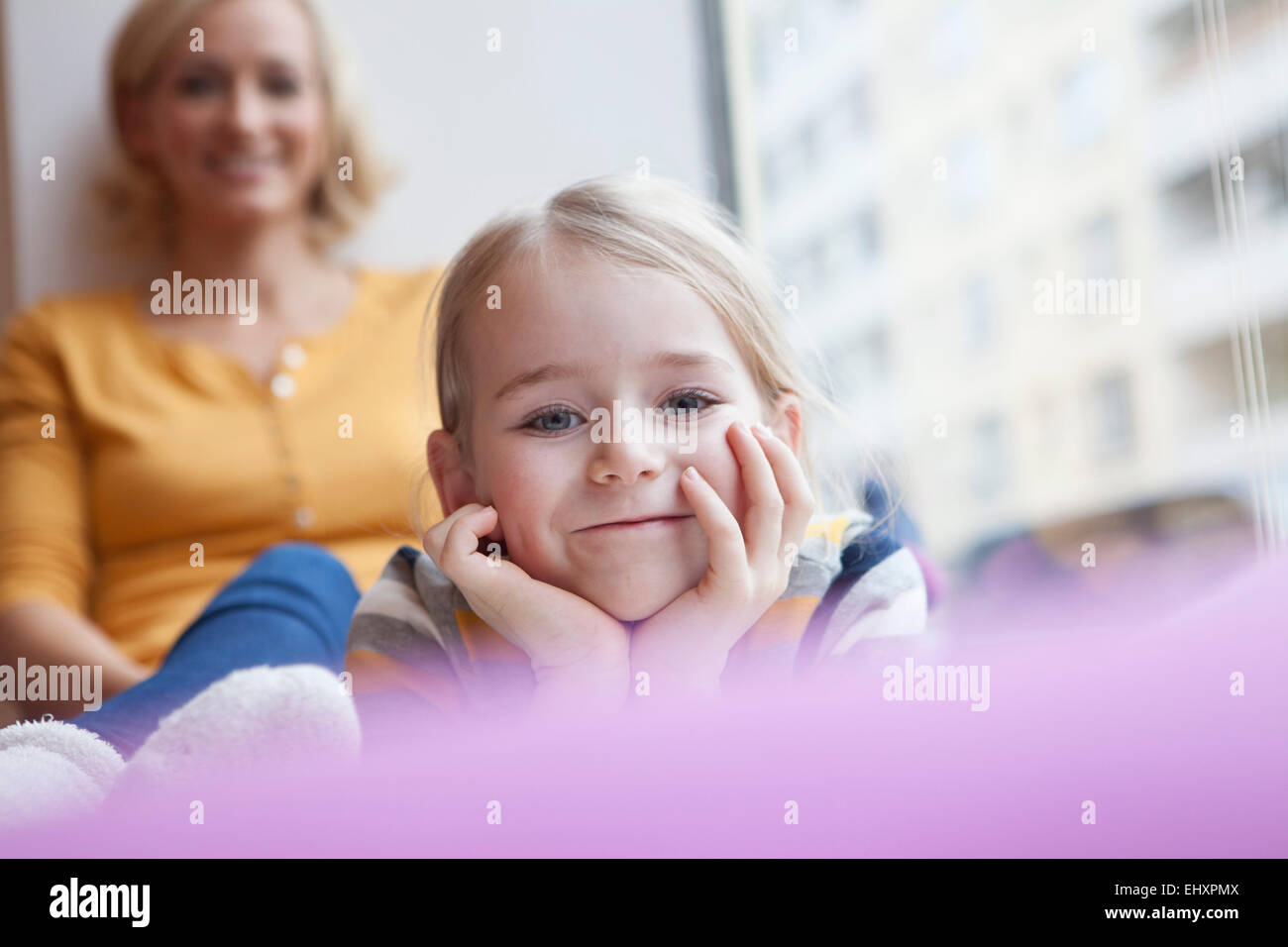 Chica sonriente con la madre en segundo plano. Foto de stock