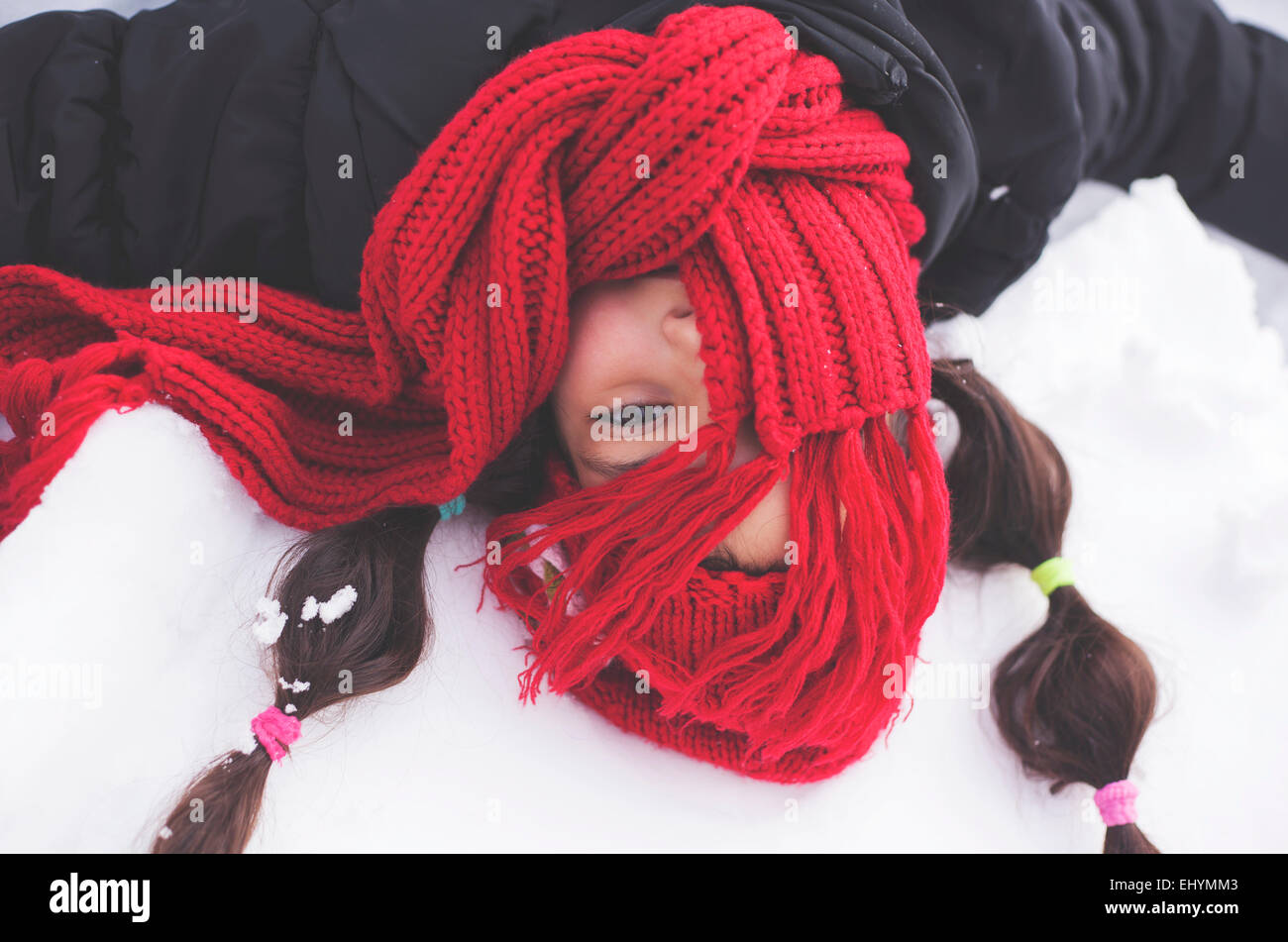 Chica con pañuelo rojo cubriendo rostro en la nieve Foto de stock