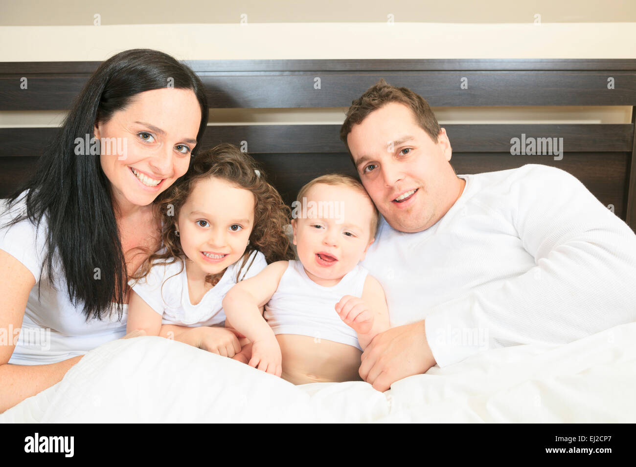 Familia Joven descansando juntos en la cama con los padres Foto de stock