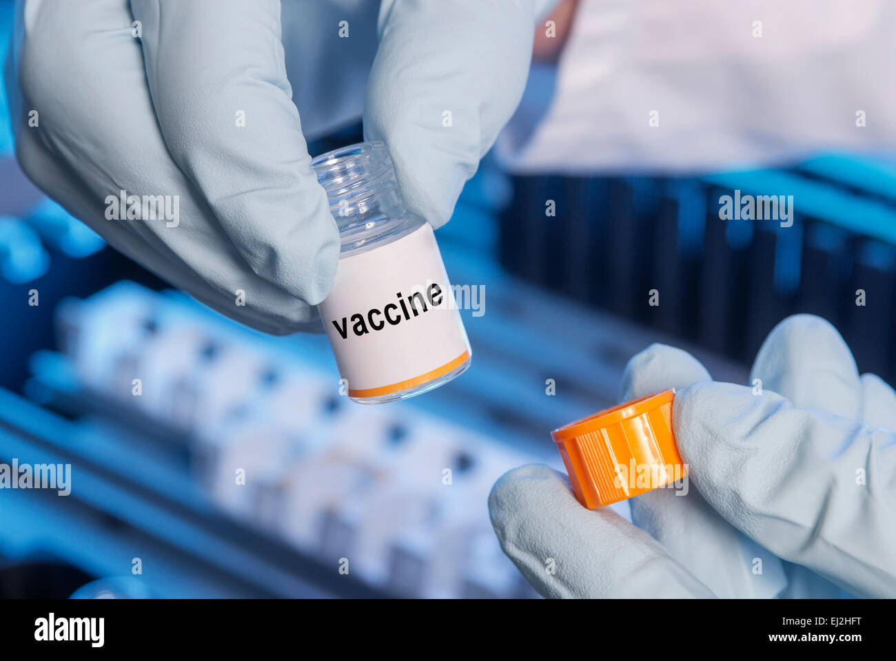 Botella pequeña con una nueva vacuna con un analizador en segundo plano. Foto de stock