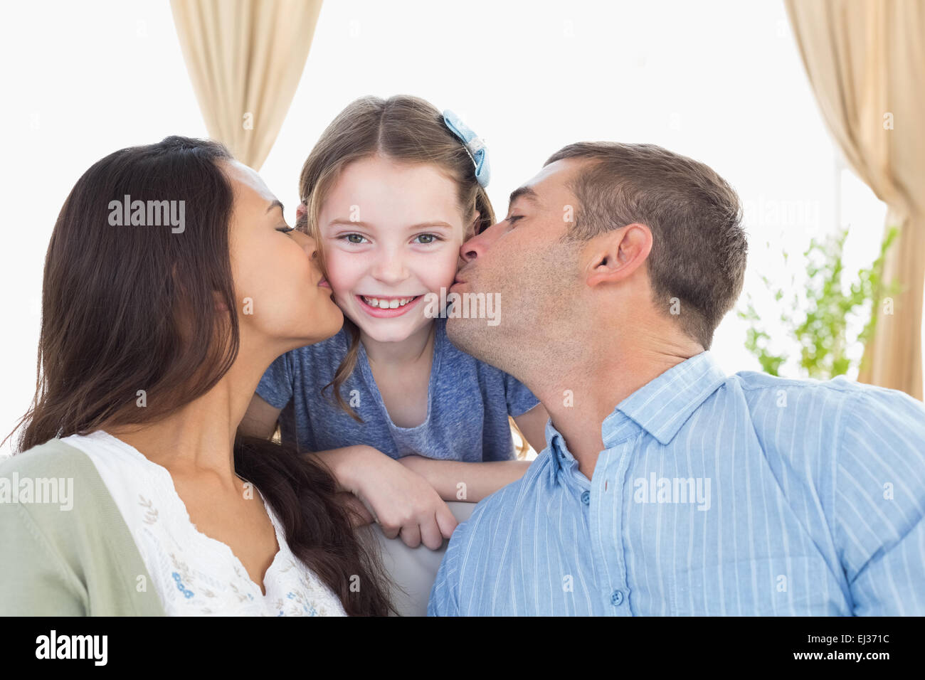 Niña feliz ser besado por los padres Foto de stock