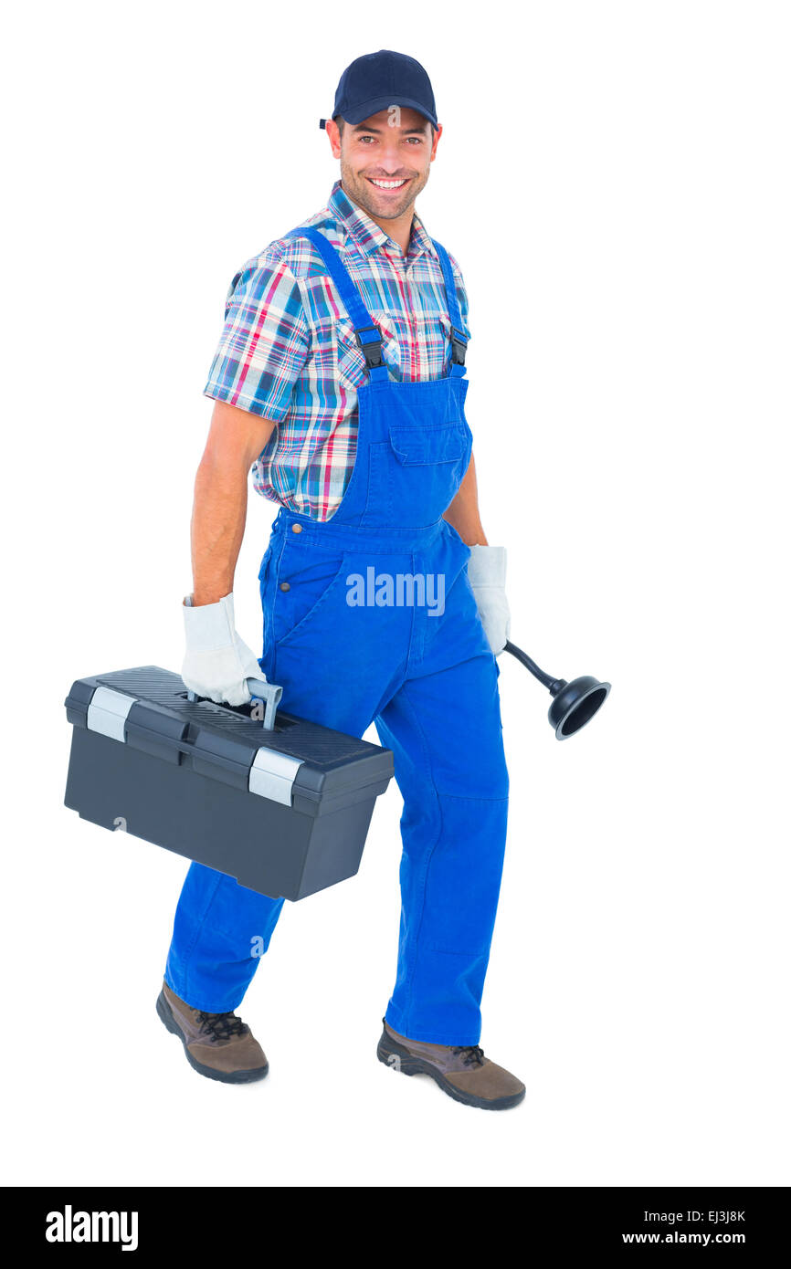 Fontanero feliz con émbolo y toolbox caminando sobre fondo blanco. Foto de stock