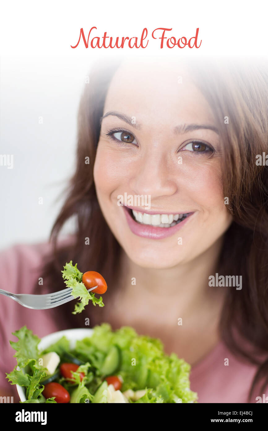Alimentos naturales contra el primer plano de una mujer sonriente con recipiente de ensalada Foto de stock