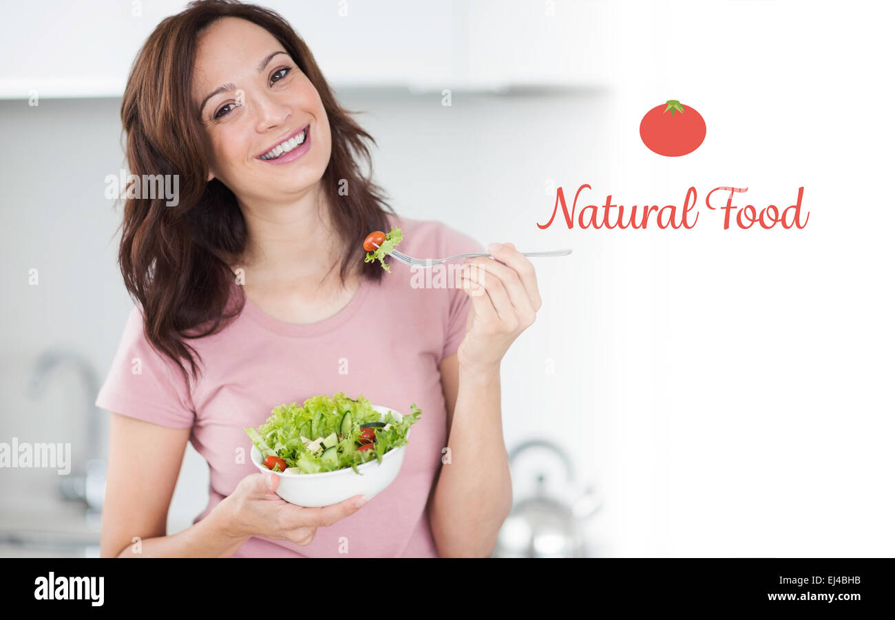 Alimentos naturales contra el retrato de mujer sonriente con un plato de ensalada en la cocina Foto de stock