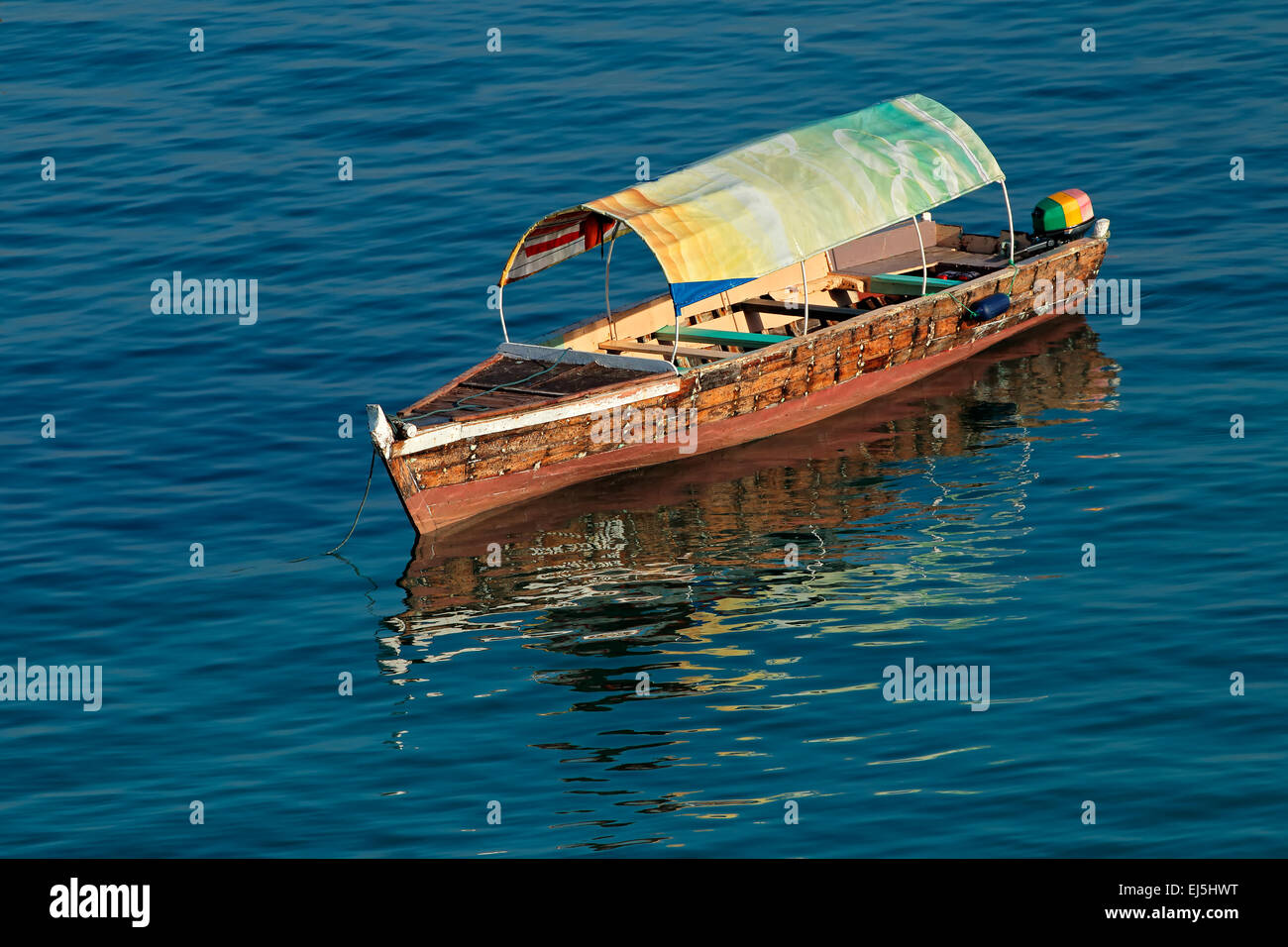 Barco de madera anclado con reflejo en el agua, la isla de Zanzíbar Foto de stock