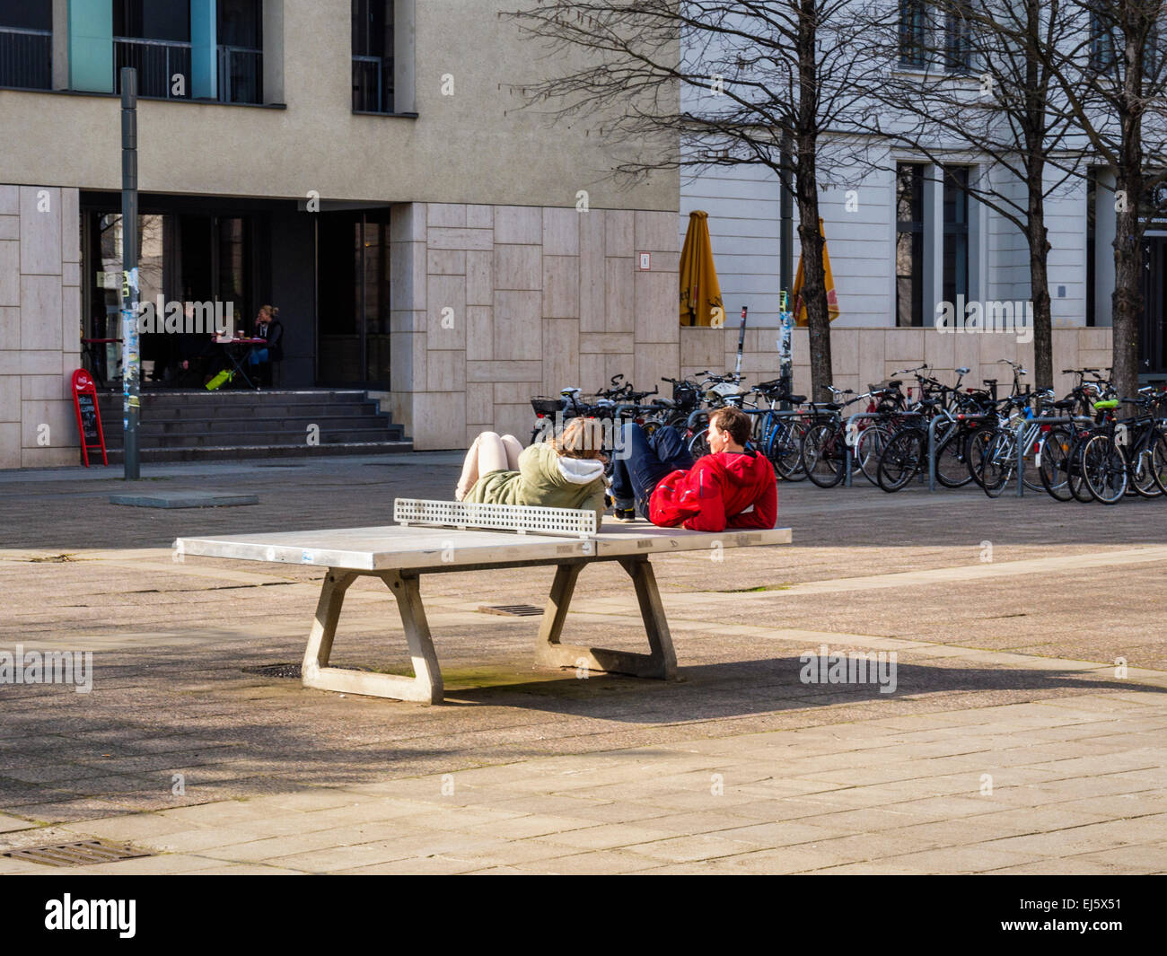 Par acostado en sol en mesa de ping-pong en el sol invernal, Mitte, Berlin Foto de stock