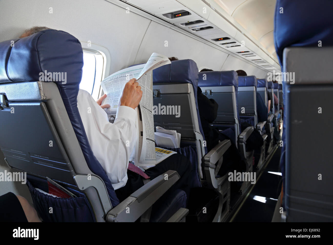 El hombre lee periódico en avión en asientos de avión Fotografía de stock -  Alamy
