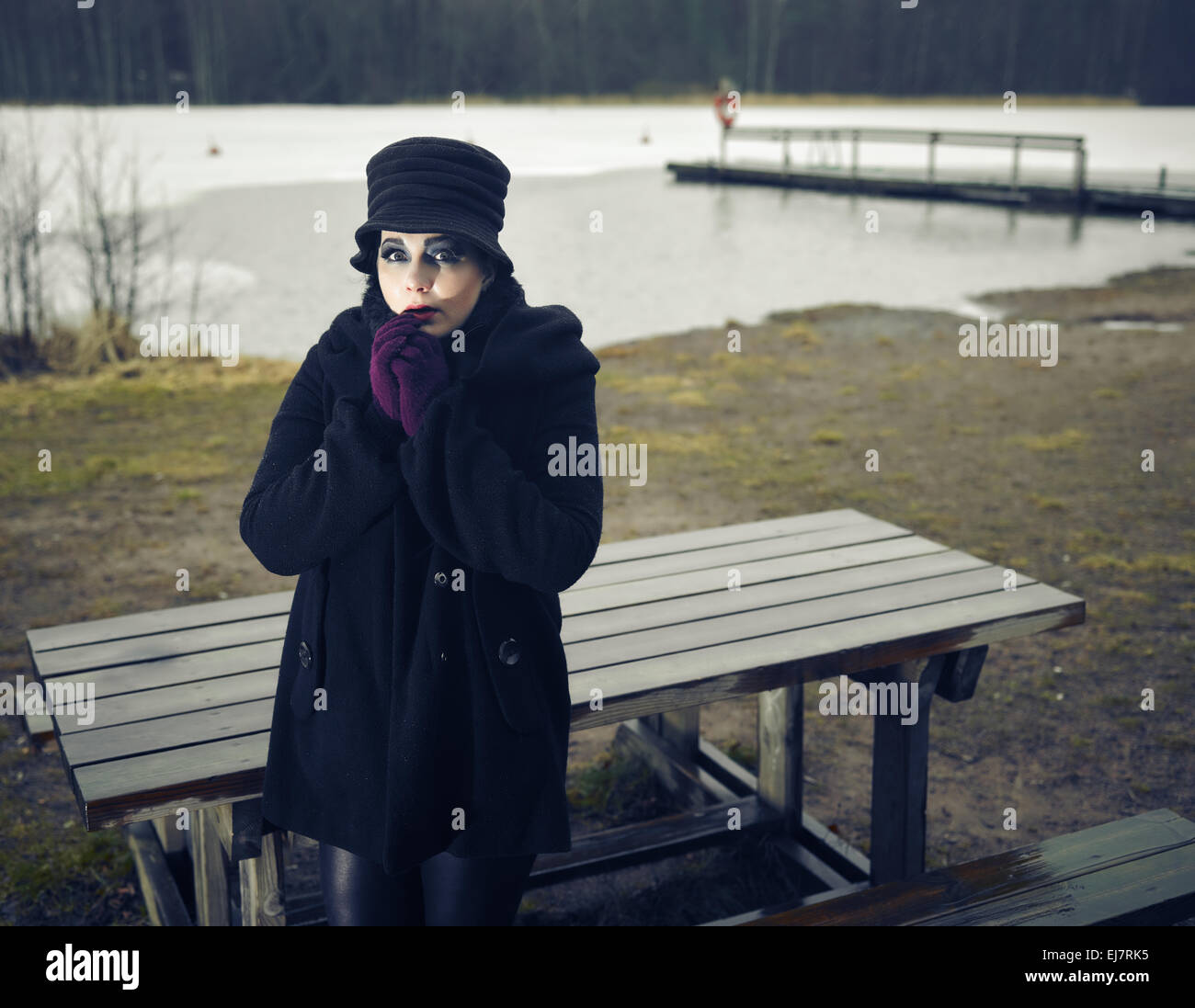 Temerosos de la moda mujer vistiendo un abrigo y sombrero y ella posando en una playa invernal, frío lluvioso, Cruz imagen procesada Foto de stock