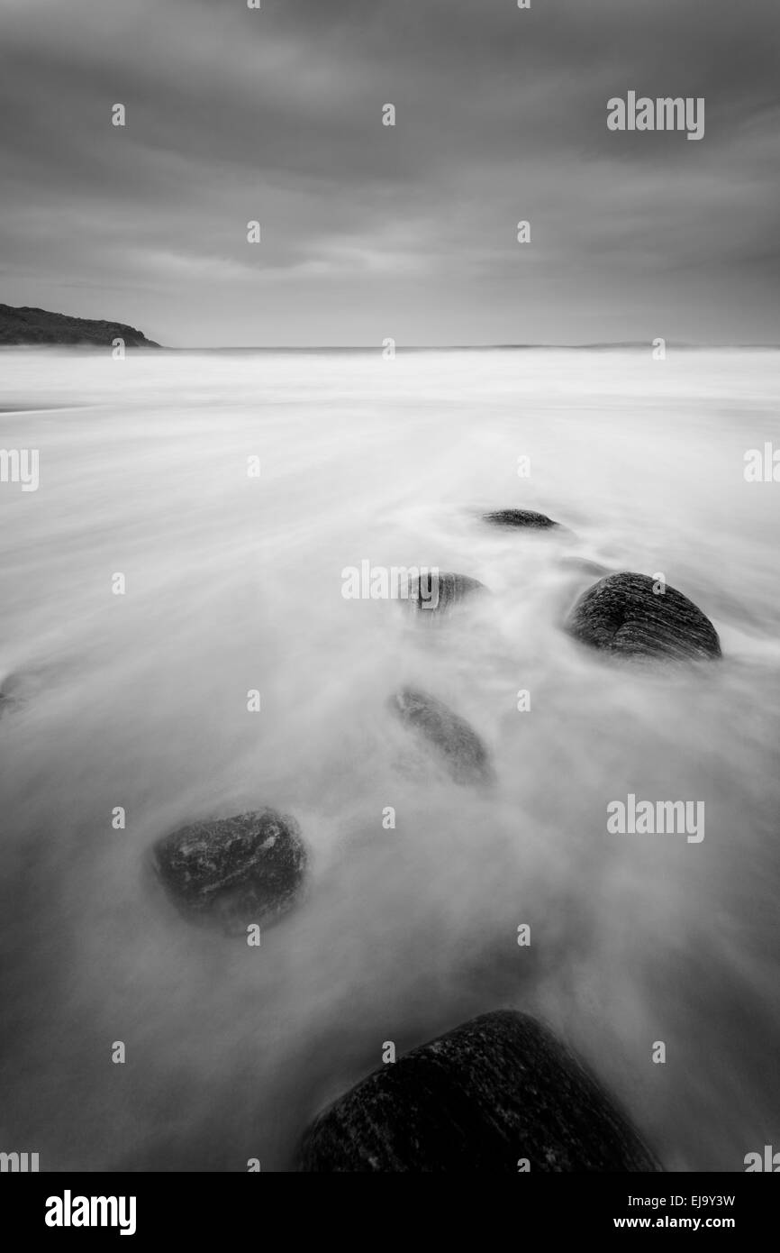 Las piedras yacen en la hermosa playa del Dail Mor como sube la marea. Foto de stock