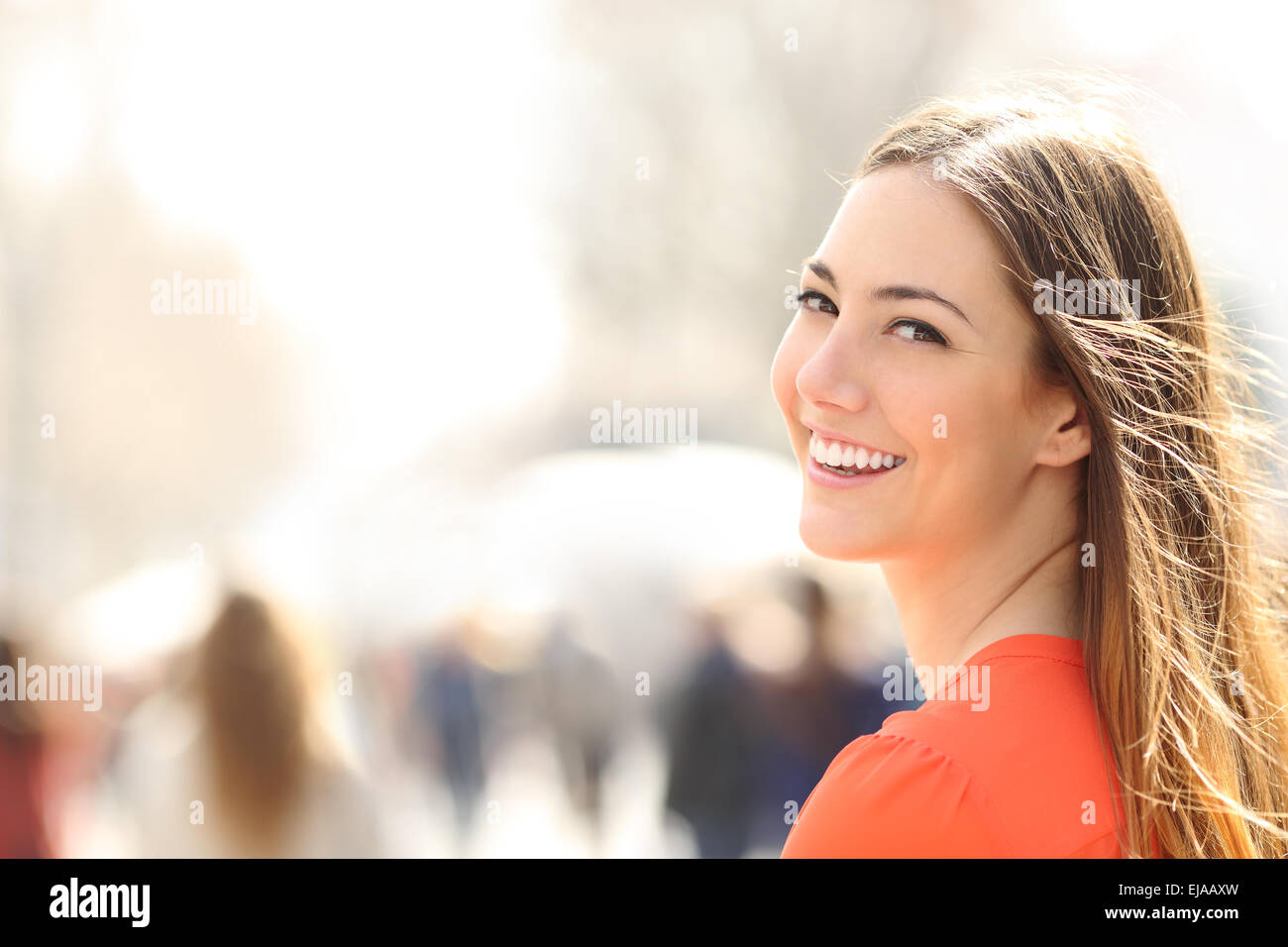 Mujer de belleza con sonrisa perfecta y dientes blancos caminando por la calle y mirando a la cámara Foto de stock