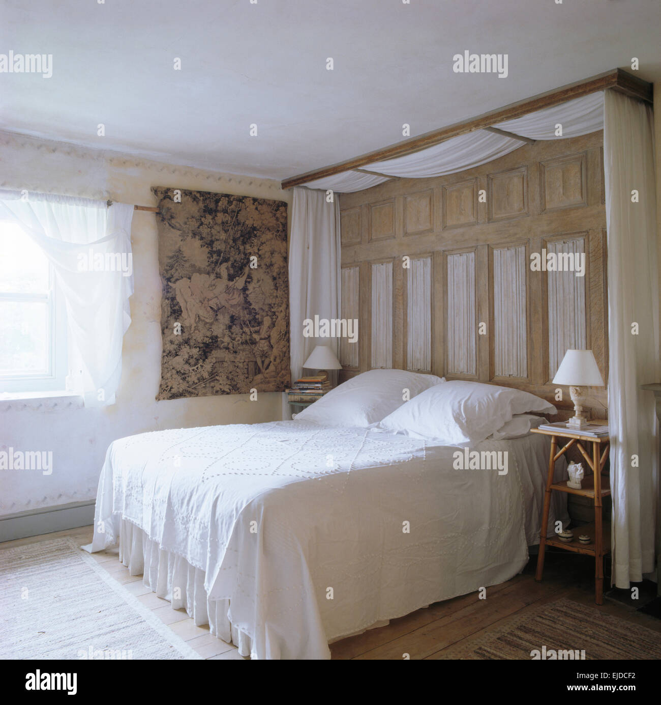 Cortinas blancas y mesas de madera encima de la cama con cubrecama blanco  en 90 dormitorio con Tapiz colgante de pared Fotografía de stock - Alamy