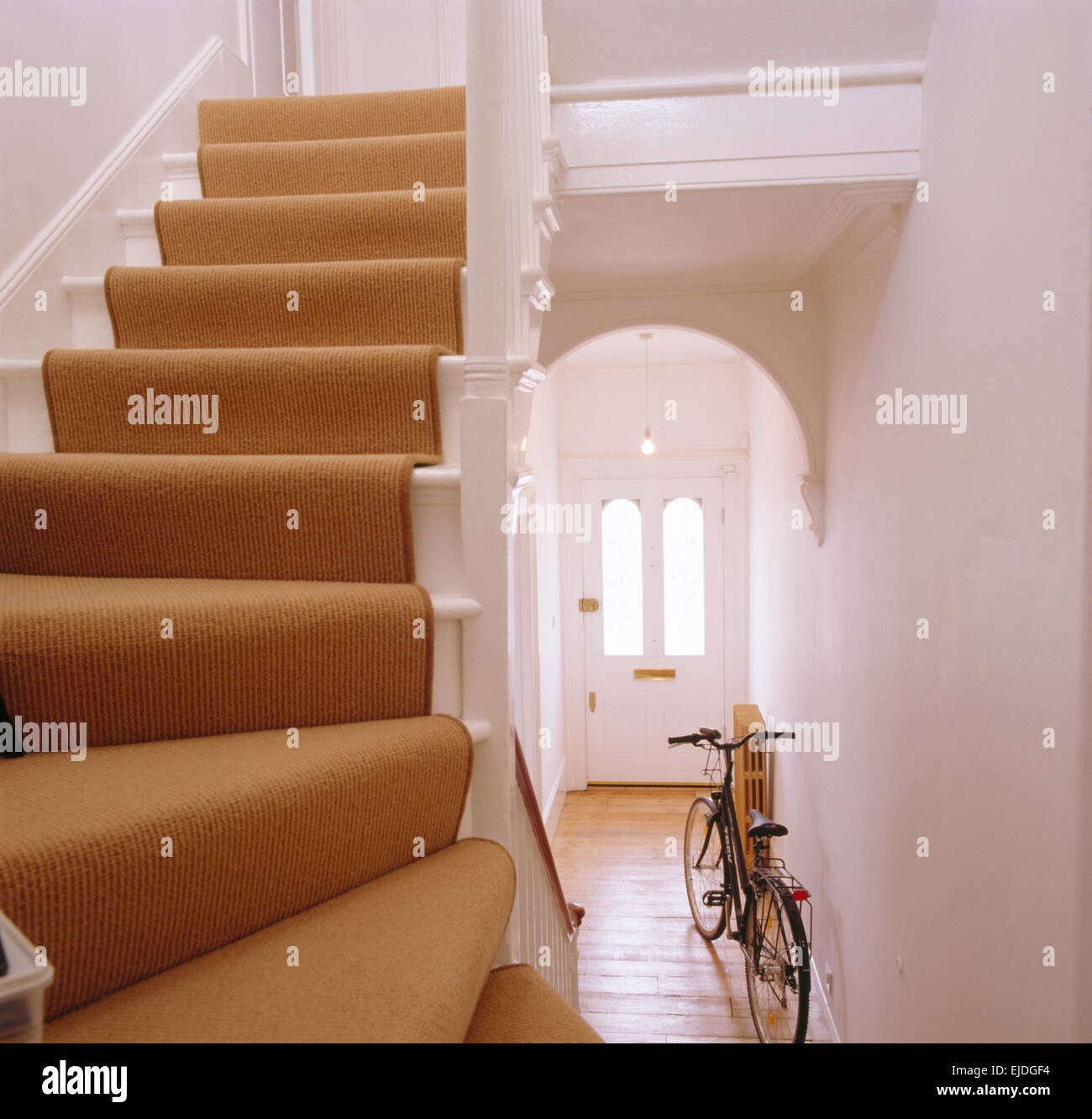 Bicicleta en casa hall con profunda crema alfombra en las escaleras Foto de stock
