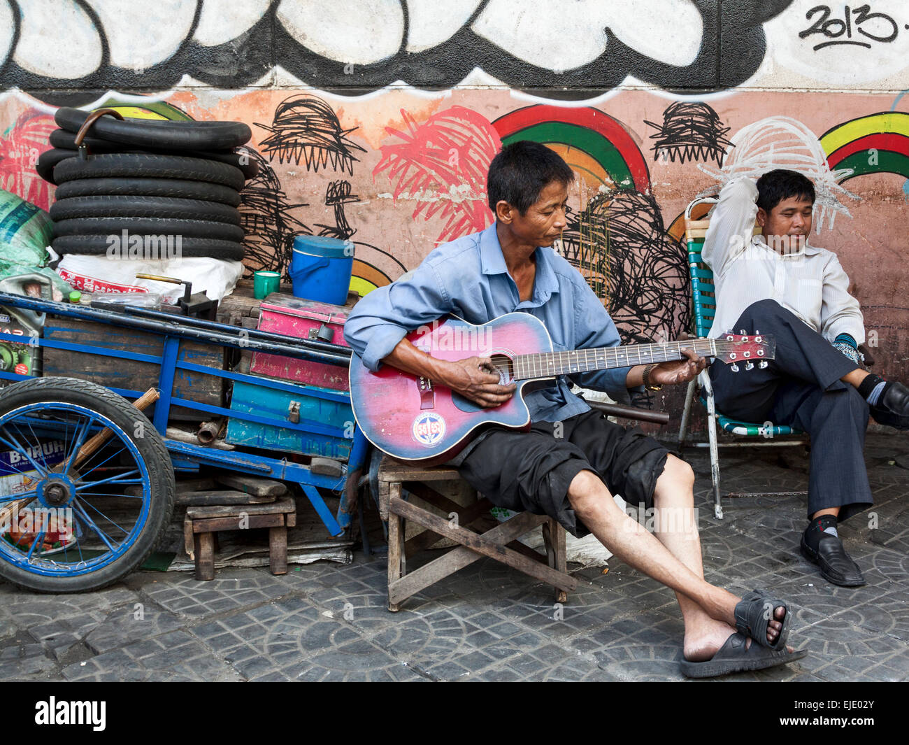 Un trabajador tocando la guitarra en la calle en Phnom Penh, Camboya, Asia. Foto de stock
