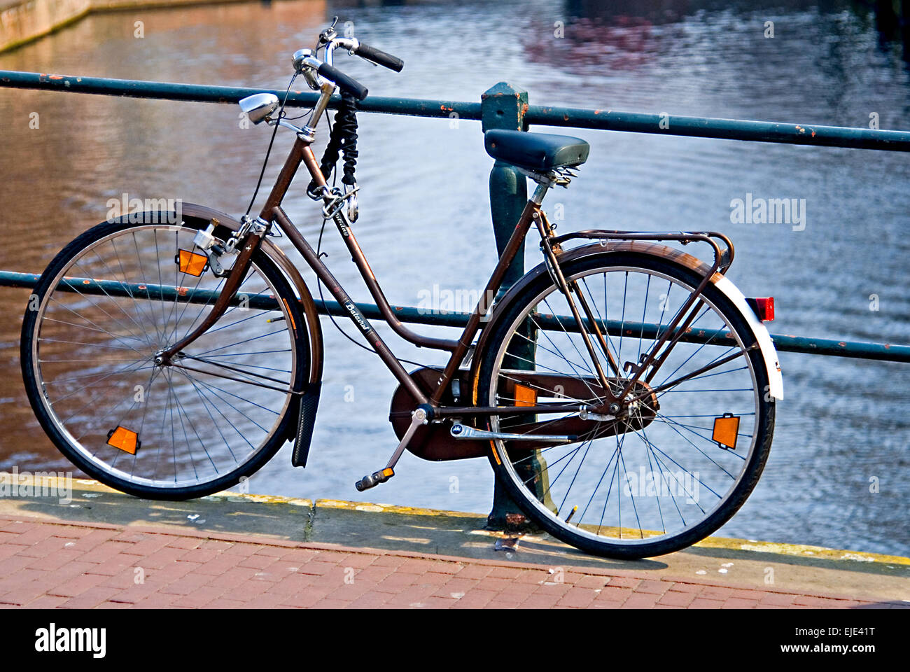 Bicicleta recostada contra barandillas en el puente del canal en Amsterdam Foto de stock