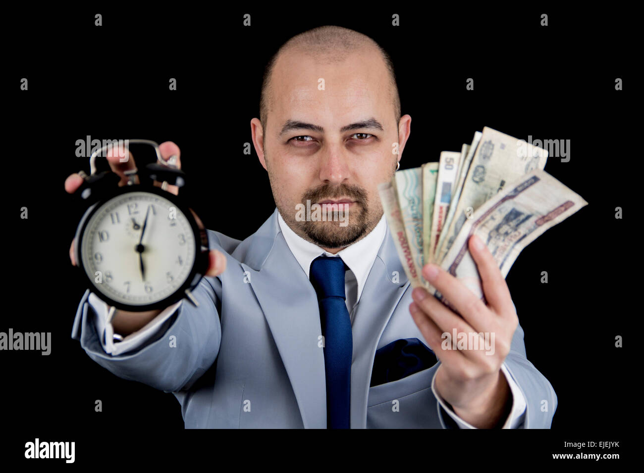 Hombre sujetando el dinero y alarma vistiendo un traje de negocios, carrera contra el reloj, la fecha límite Foto de stock