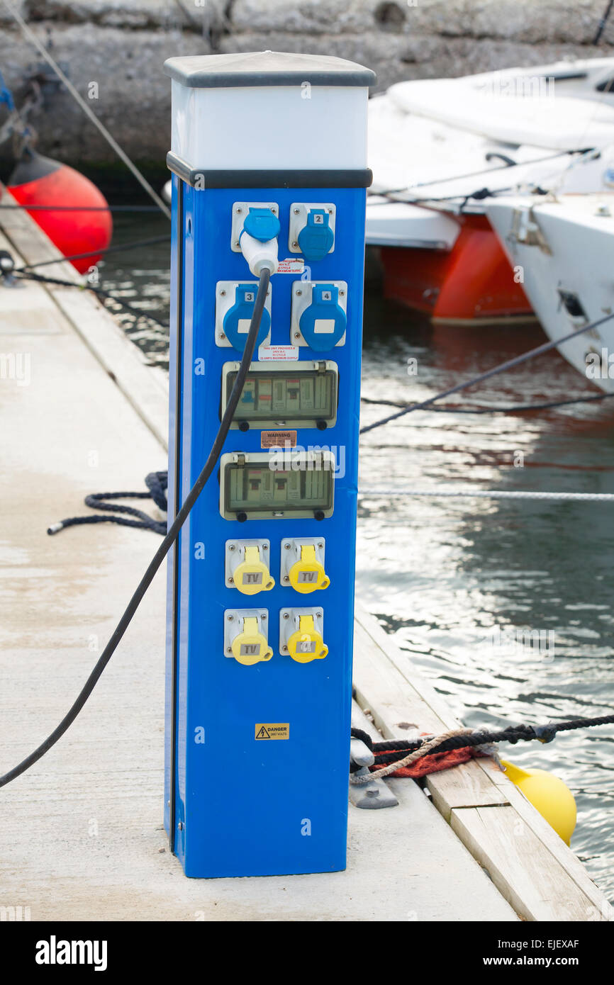 Fuente de alimentación azul caso destaca sobre muelle flotante en el pequeño puerto deportivo Foto de stock