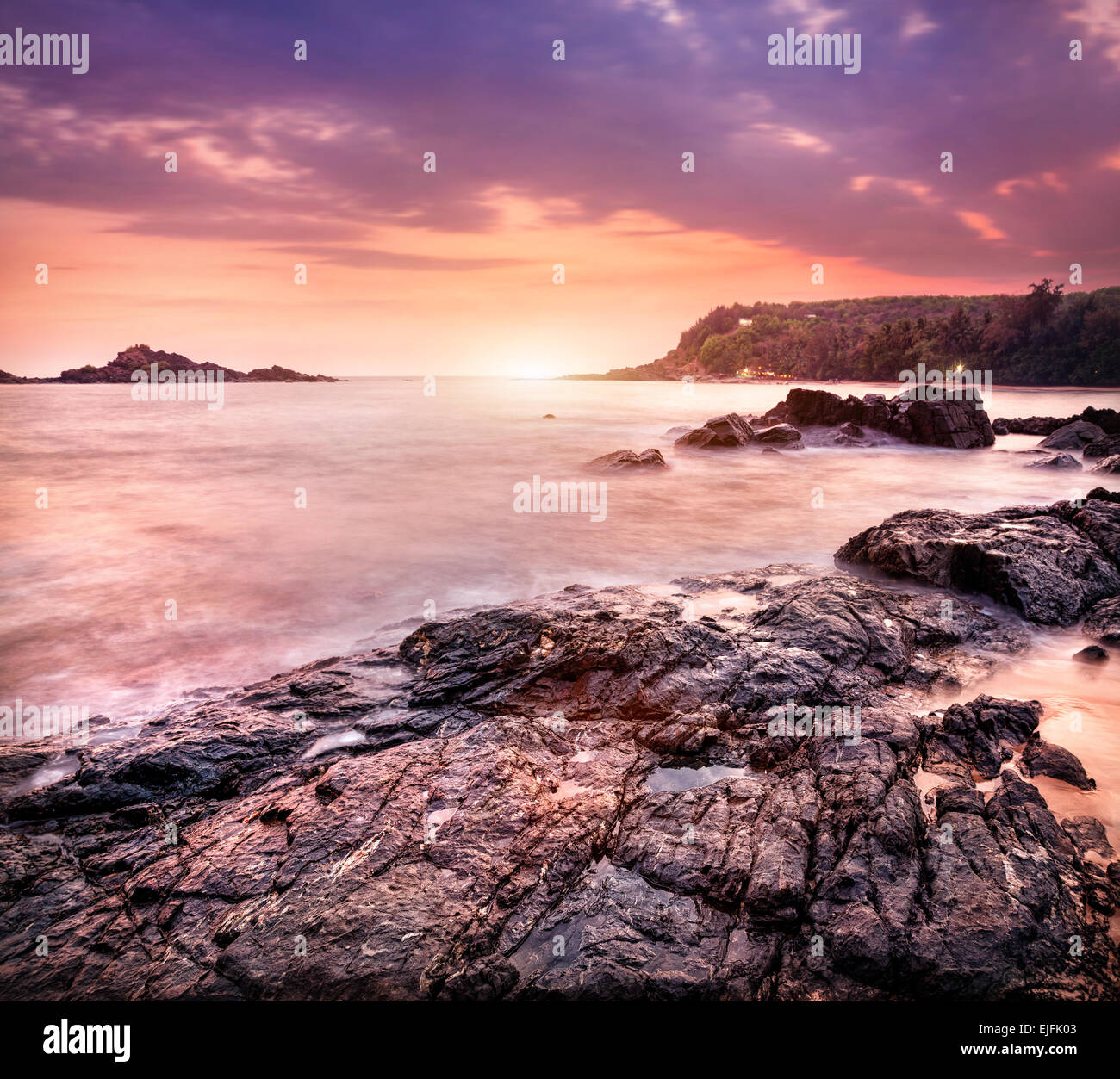 Mar con rocas en violet sunset sky en Om beach, Gokarna, Karnataka, India Foto de stock