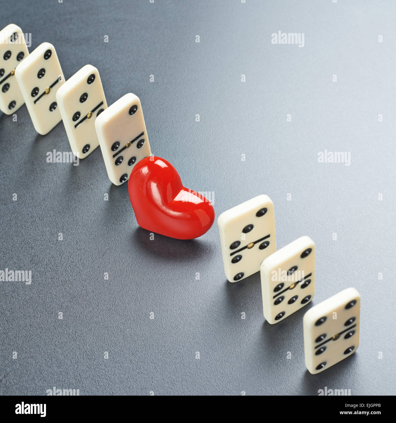 Corazón rojo entre las piezas de domino Foto de stock