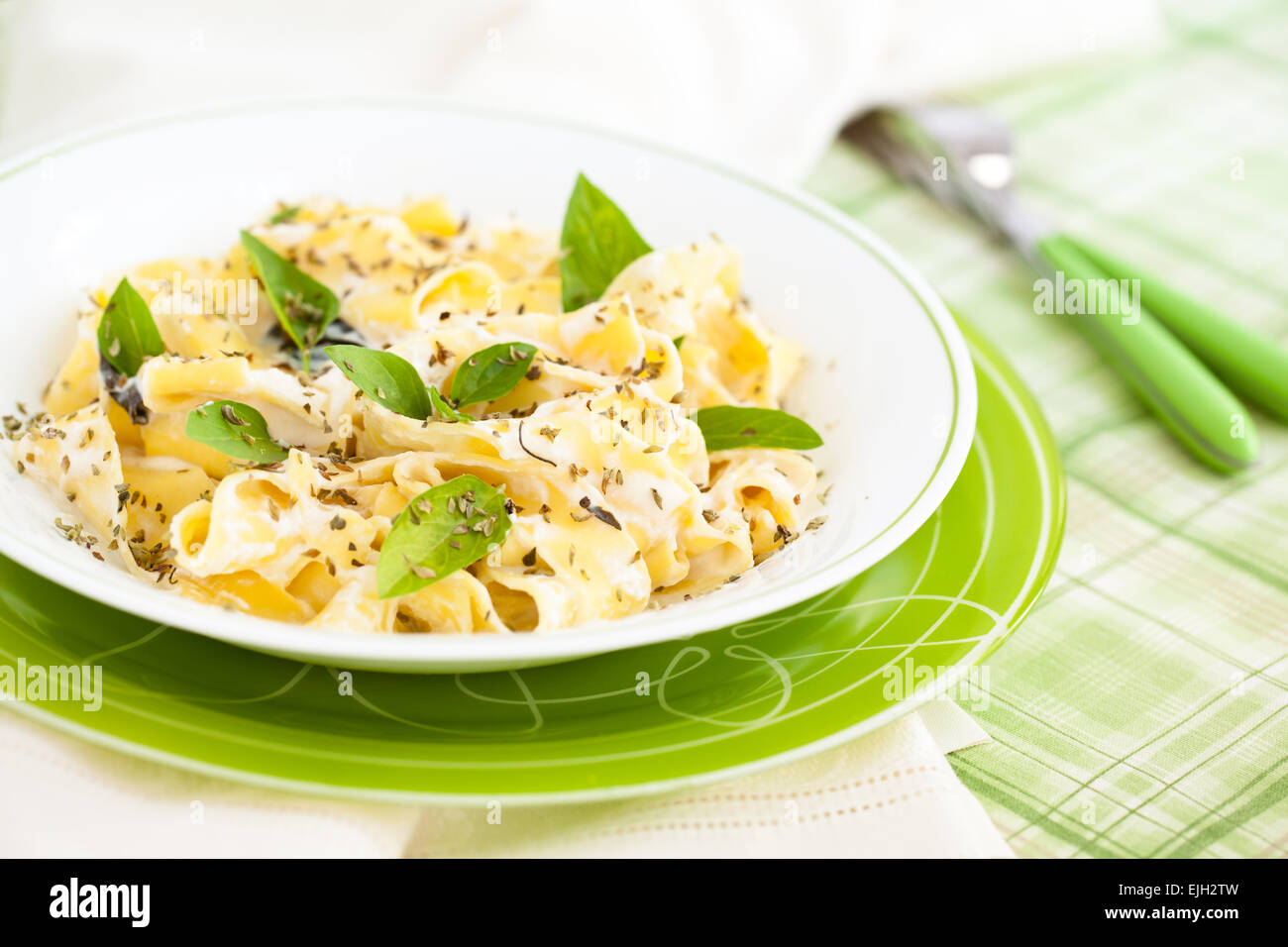 Pasta italiana con salsa de queso y hojas de albahaca. Foto de stock