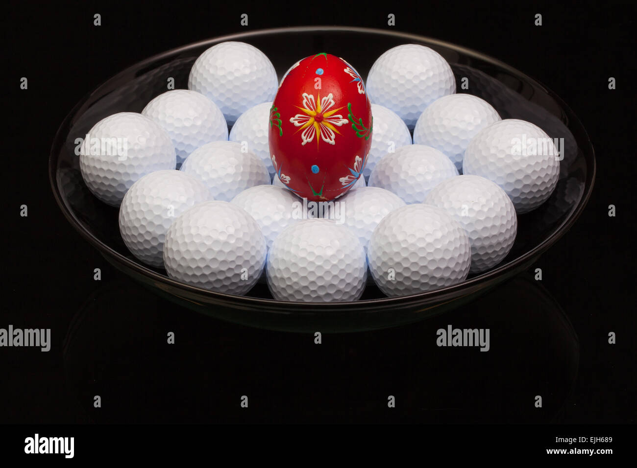 Las bolas de golf y el huevo en un tazón negro Foto de stock