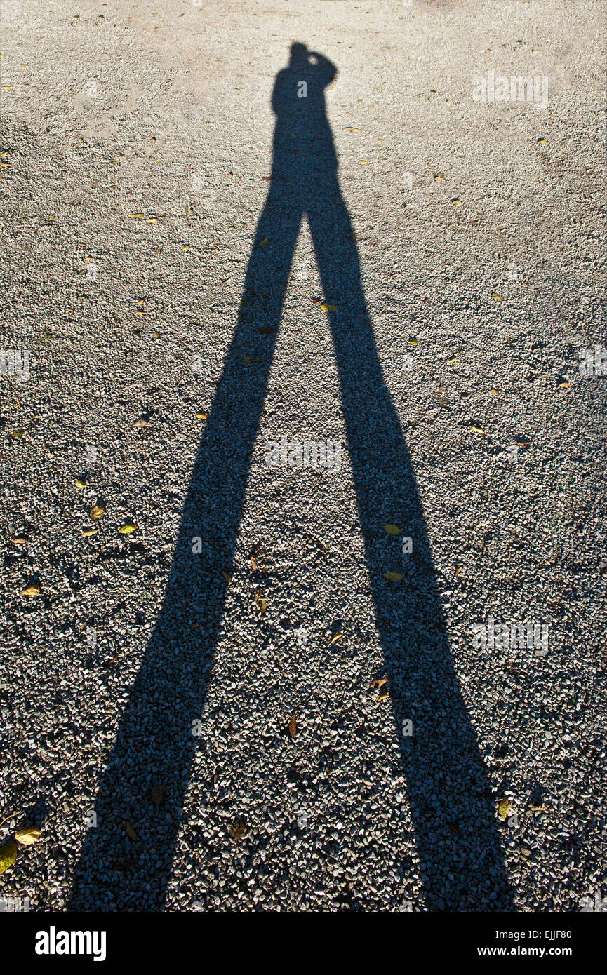 La sombra de un hombre en Pebble grava fotografiando a sí mismo Foto de stock