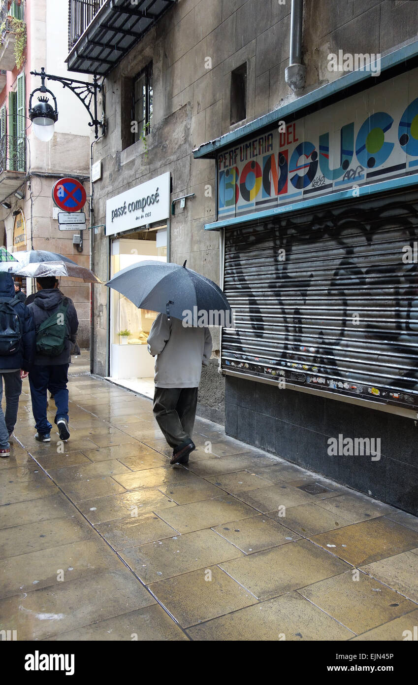 Las personas con paraguas caminando bajo la lluvia a lo largo de calle en  el barrio del Raval de Barcelona, Cataluña, España Fotografía de stock -  Alamy