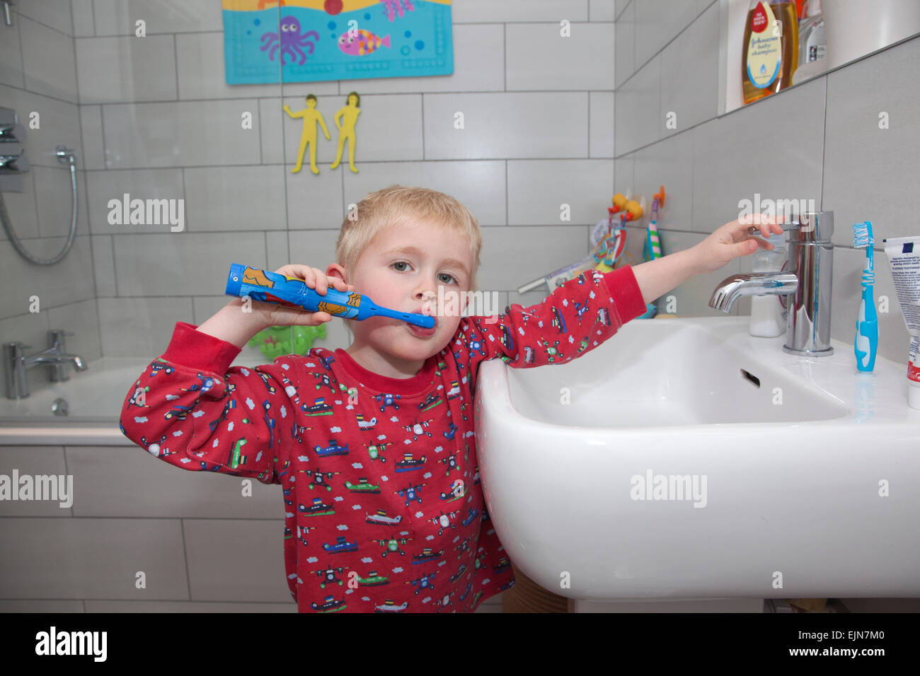 Cuatro años de edad el cepillado sus dientes con un cepillo dental eléctrico en el baño antes de acostarse, REINO UNIDO Foto de stock