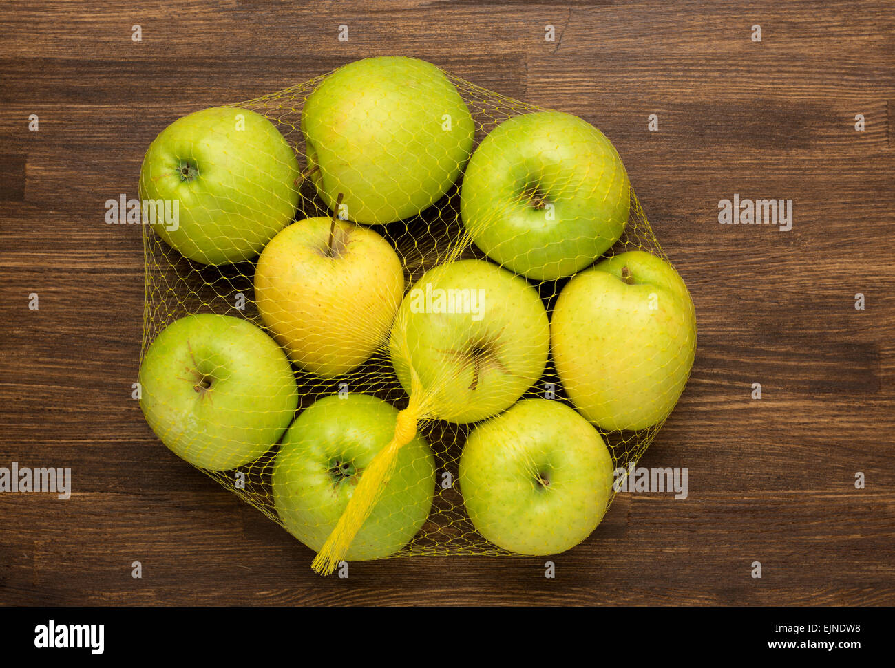 Montón de manzanas en la malla de la tienda en madera Foto de stock