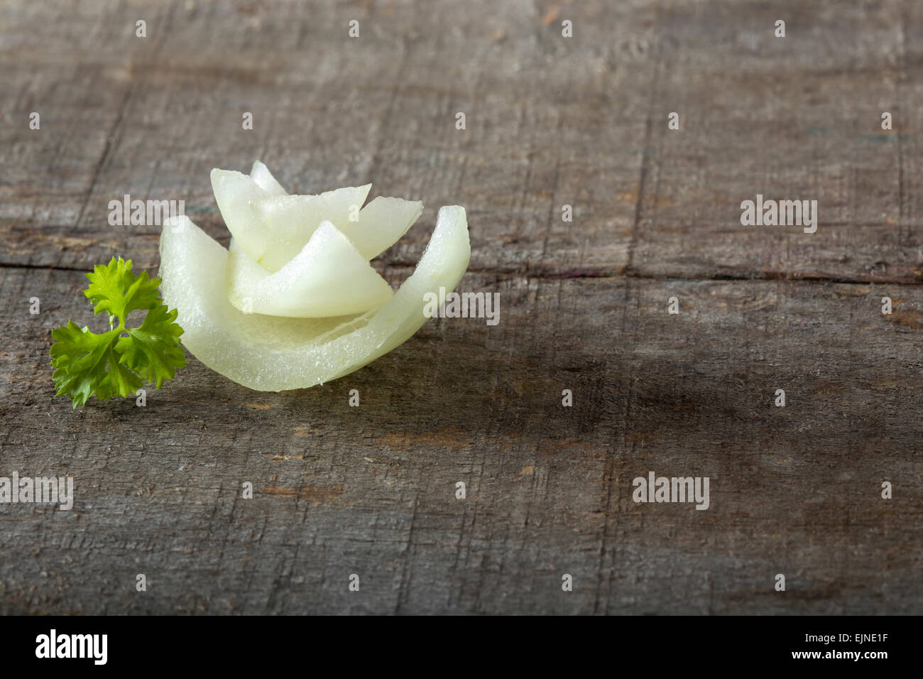 Rodajas de cebolla blanca y perejil en placa de madera Foto de stock