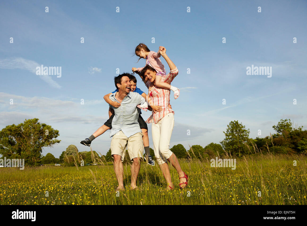 Una familia, dos padres afuera en el verano dando se superpone a dos niños. Foto de stock