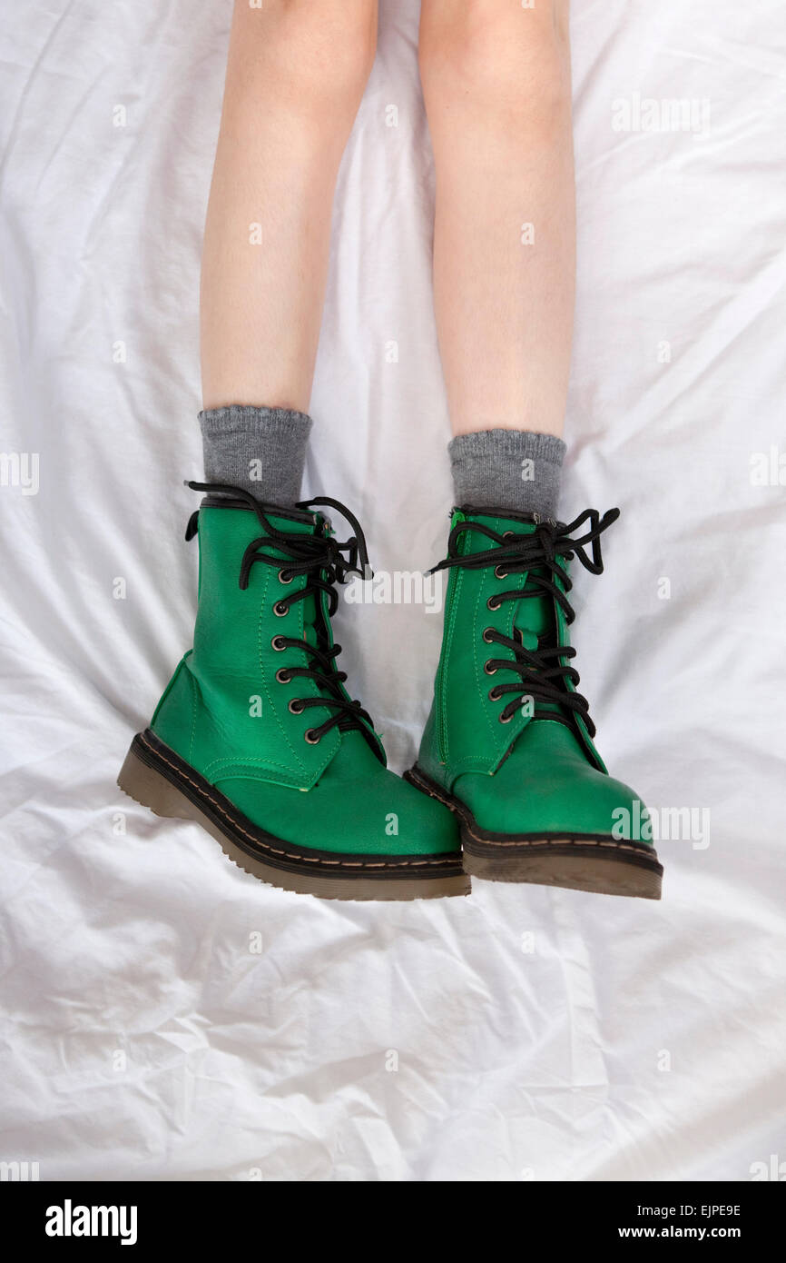 Chica en verde botas estilo Doc Marten, tumbado sobre un blanco, arrugado  bedsheet Fotografía de stock - Alamy
