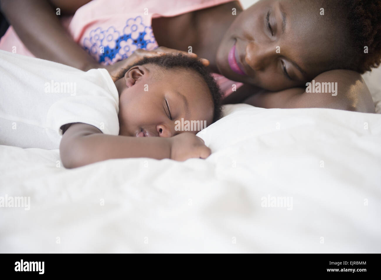 Madre Negra admirando hijo dormido en la cama Foto de stock