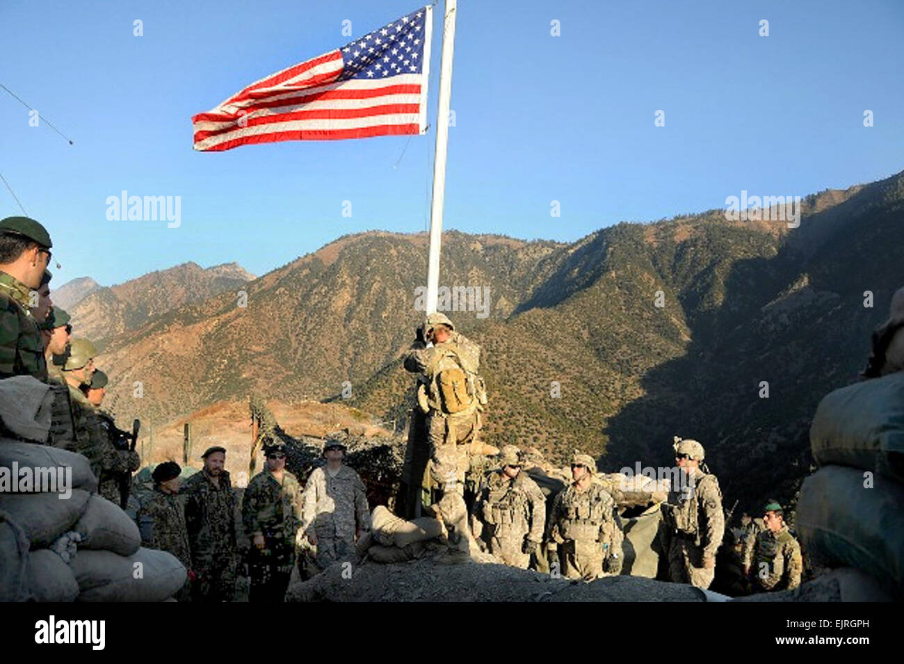 Un suboficial del ejército de Estados Unidos se prepara para bajar la bandera norteamericana durante una transferencia de autoridad ceremonia en el puesto de observación Mace, como Estados Unidos y tropas del Ejército Nacional Afgano mira en la provincia de Kunar, Afganistán, el 21 de diciembre de 2010. Los soldados están asignados a la 101ª División Aerotransportada del primer escuadrón, 32º Regimiento de Caballería, 1ª Brigada equipo de combate. OP Mace es el más septentrional de puesto de observación en la provincia afgana de Kunar, en la frontera con el Pakistán. El capitán Pedro Shinn Foto de stock