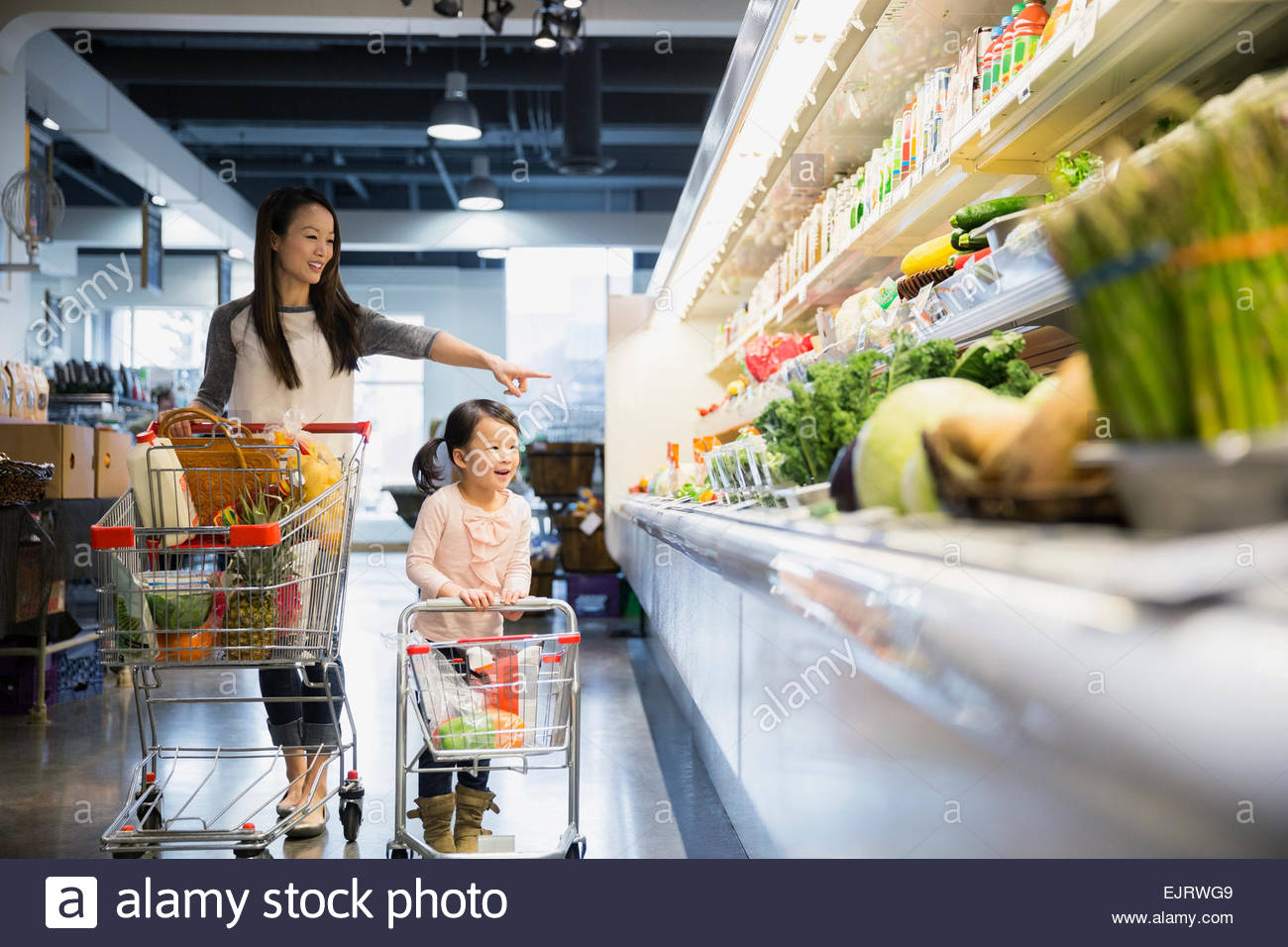 Madre e hija empujando carritos de la compra en la tienda Foto de stock