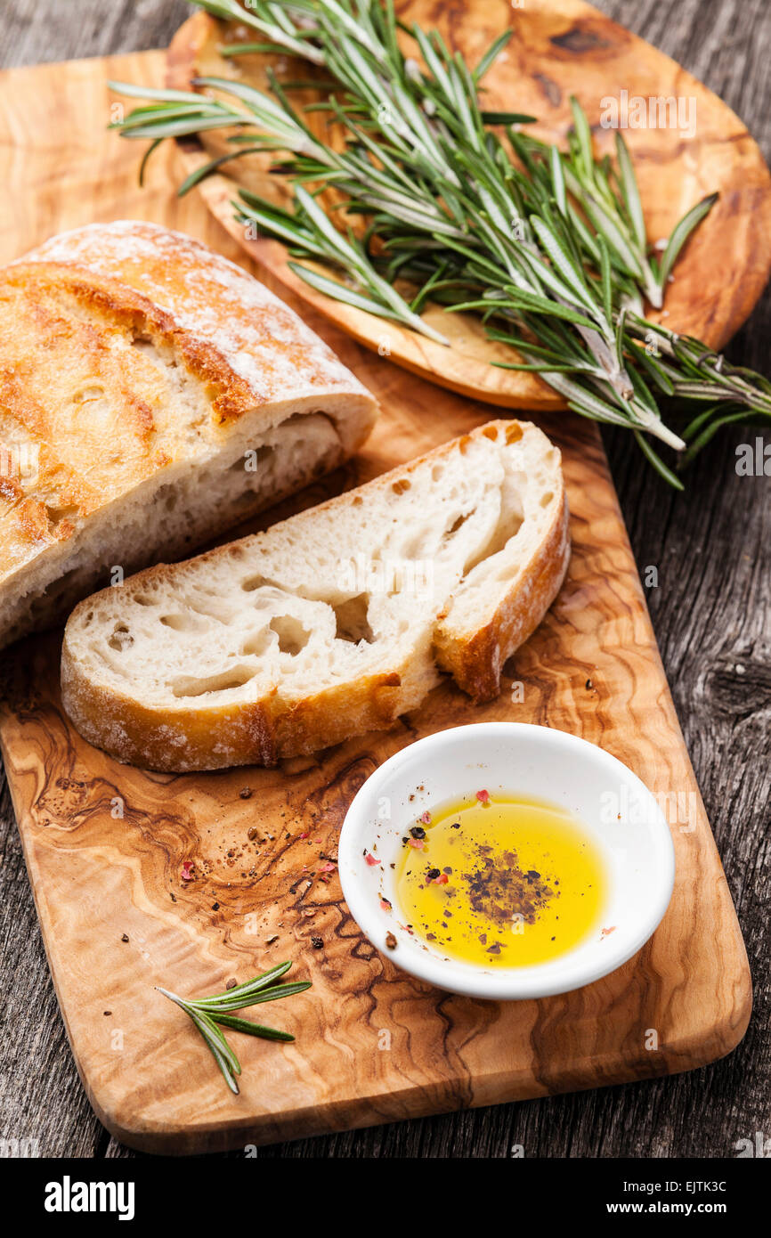 Rebanadas de pan ciabatta y aceite de oliva virgen extra Aceite de oliva utensilios de madera antecedentes Foto de stock