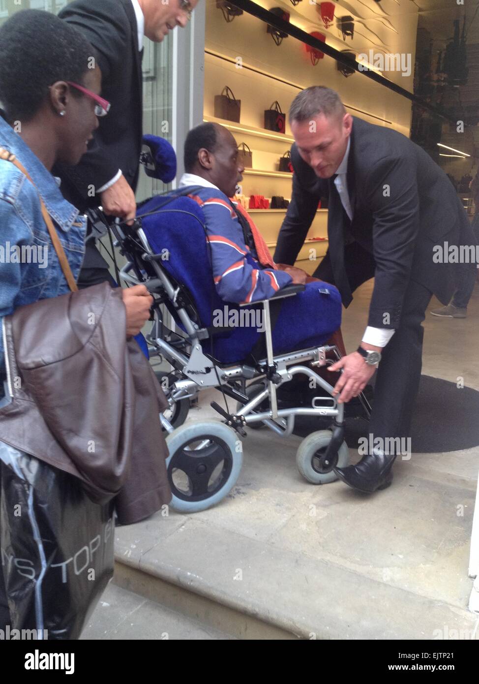 Un hombre con discapacidad es llevado por los guardias de seguridad en Victoria  Beckham, la nueva tienda debido a la tienda no tiene acceso para silla de  ruedas. Que incluye: un hombre