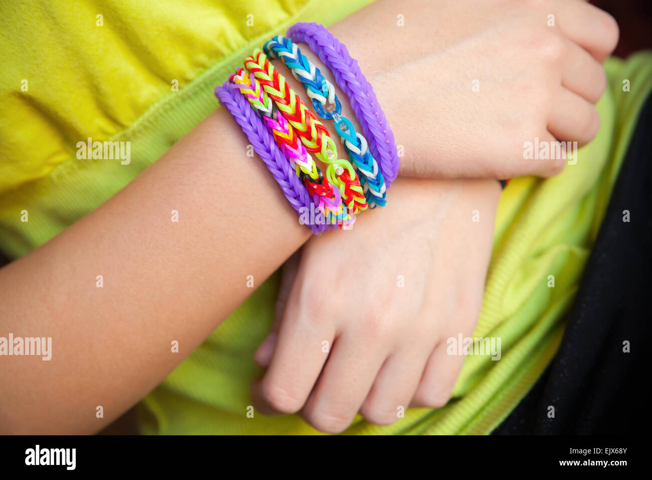 Manos del niño con banda de goma de colores rainbow telar pulseras de moda, accesorios de moda para niños Foto de stock