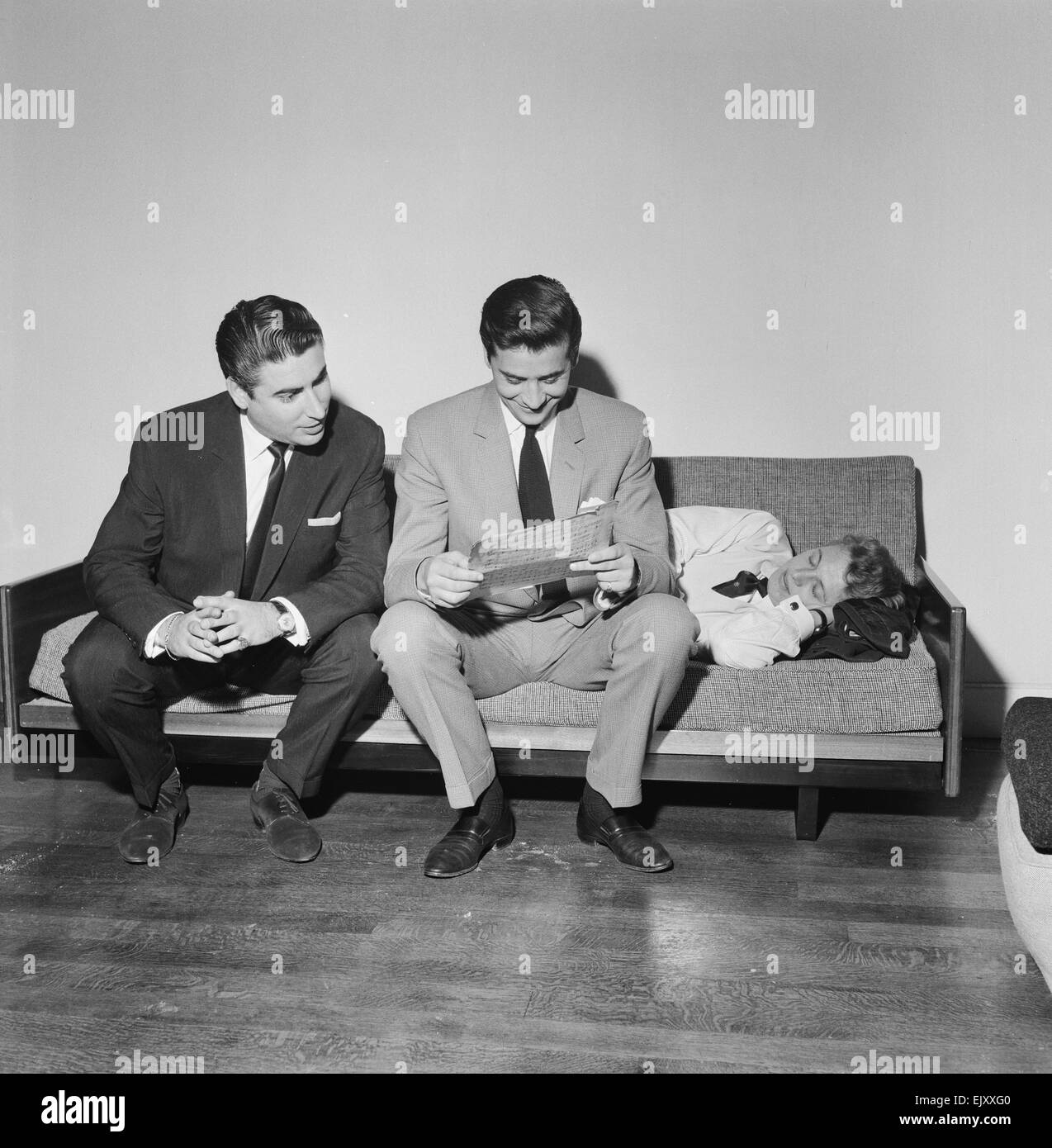 Larry Parnes (izq.) y John Kennedy (centro), gestores de la cantante Tommy Steele, quien es retratada durmiendo en el sofá, 28 de abril de 1961. *** Título Local *** Lawrence Parnes Manager Foto de stock