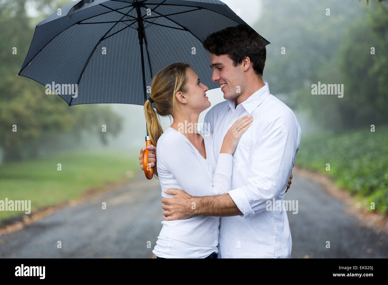Joven pareja amorosa con paraguas en la lluvia Fotografía de stock - Alamy