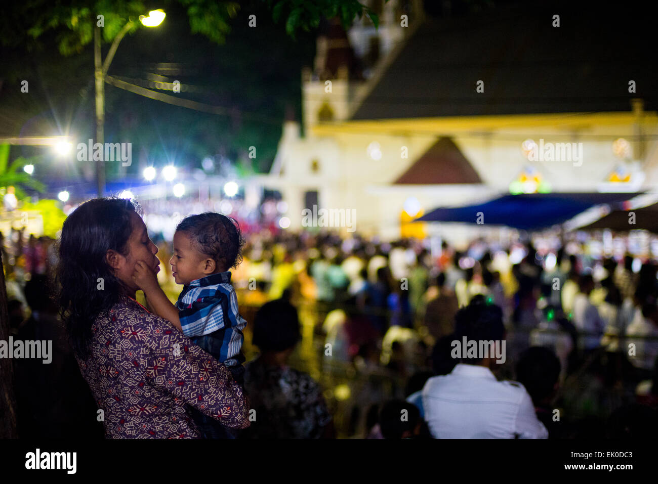 Larantuka, Indonesia. 3rd de abril de 2015. Una madre calma a su hijo durante la ceremonia de misa del Jueves Santo en la iglesia de la Catedral en Larantuka, Isla Flores, Indonesia. Foto de stock