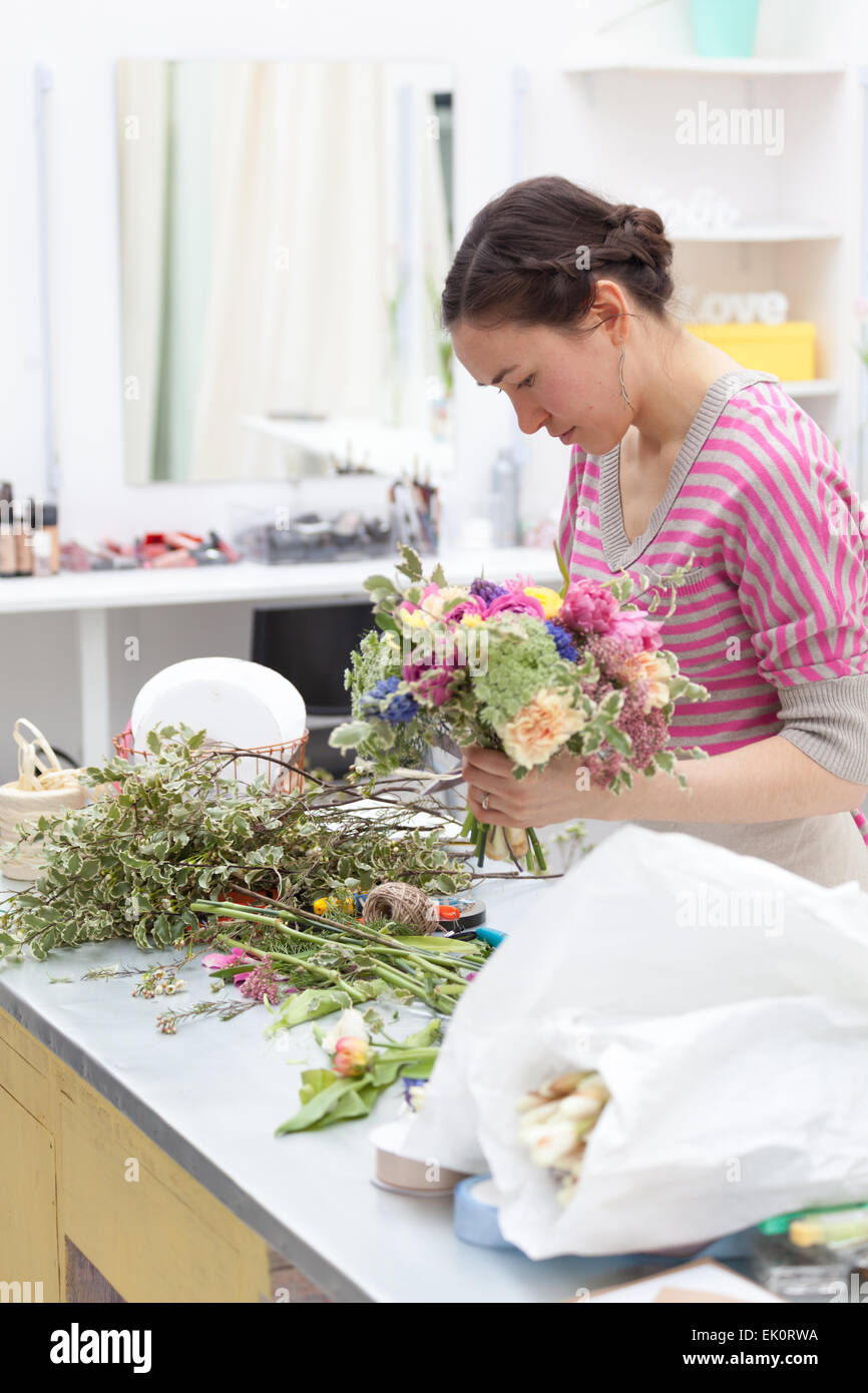 Masterclass de floristería sonriente en el trabajo con el ramo de flores Foto de stock