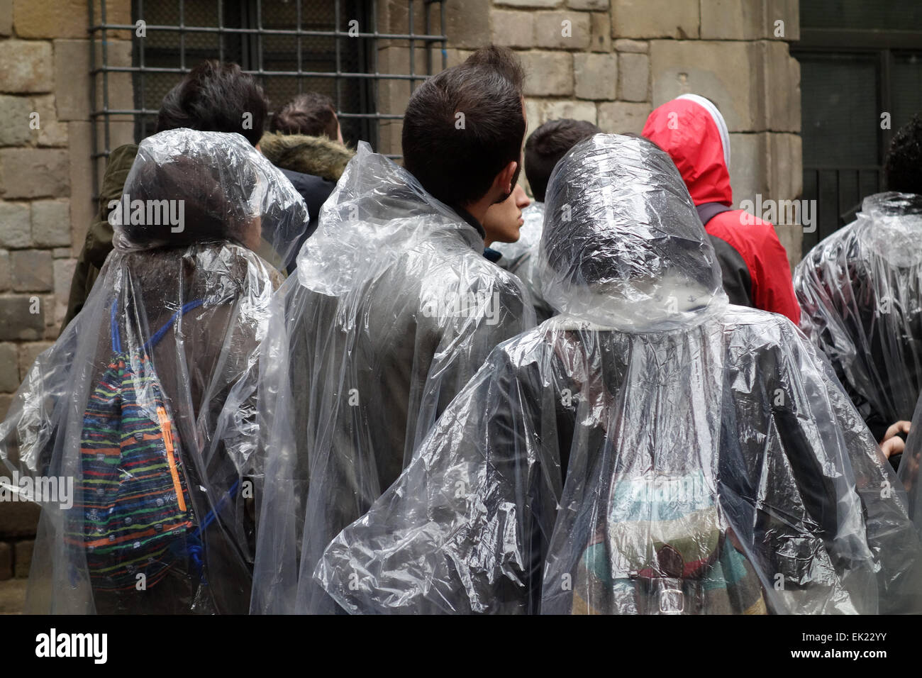 Grupo de jóvenes turistas vistiendo impermeables de plástico en día lluvioso en la Plaça de Sant Felip Neri, Barrio Gótico, Barcelona Foto de stock