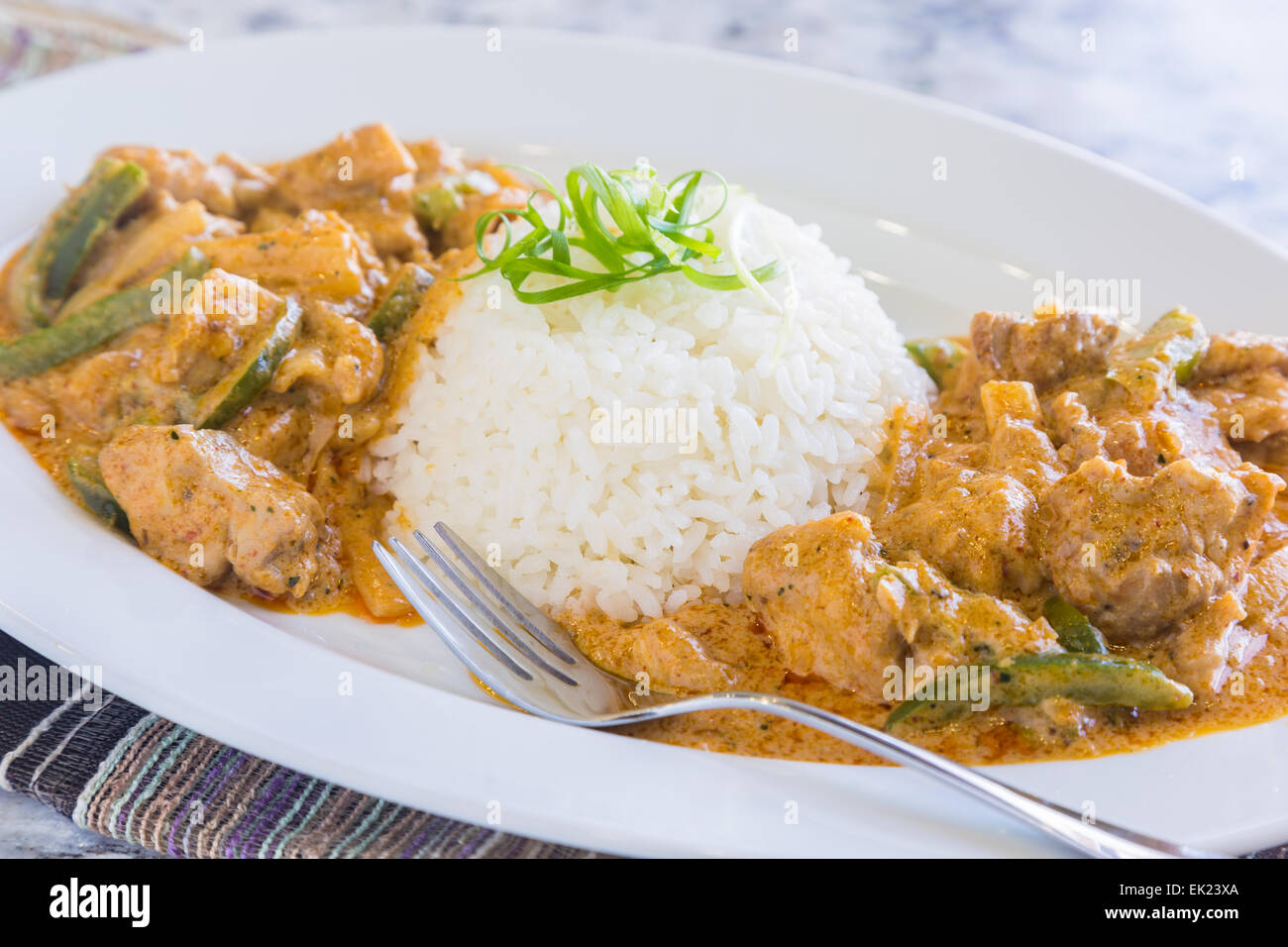 Muslos de pollo y de pimiento verde en salsa de curry panang, servido con arroz Foto de stock