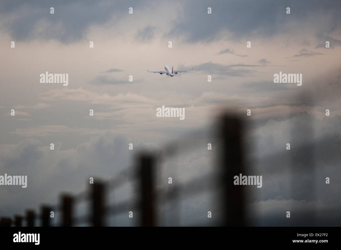 Airbus despega en cielo nublado entre capas de nubes con vallado perimetral silueta Foto de stock