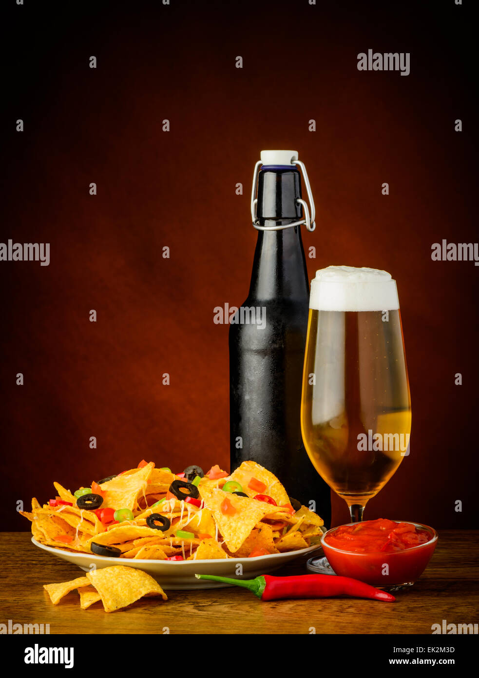 Bodegón con nachos, salsa y dip de vidrio y botellas de cerveza Foto de stock