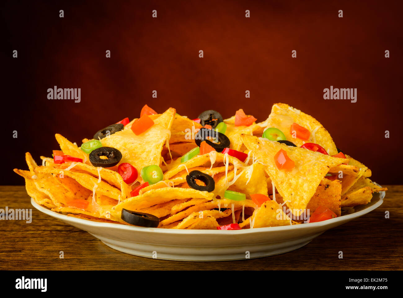 Tortilla Chips nachos con queso, aceitunas y chiles en una placa Foto de stock