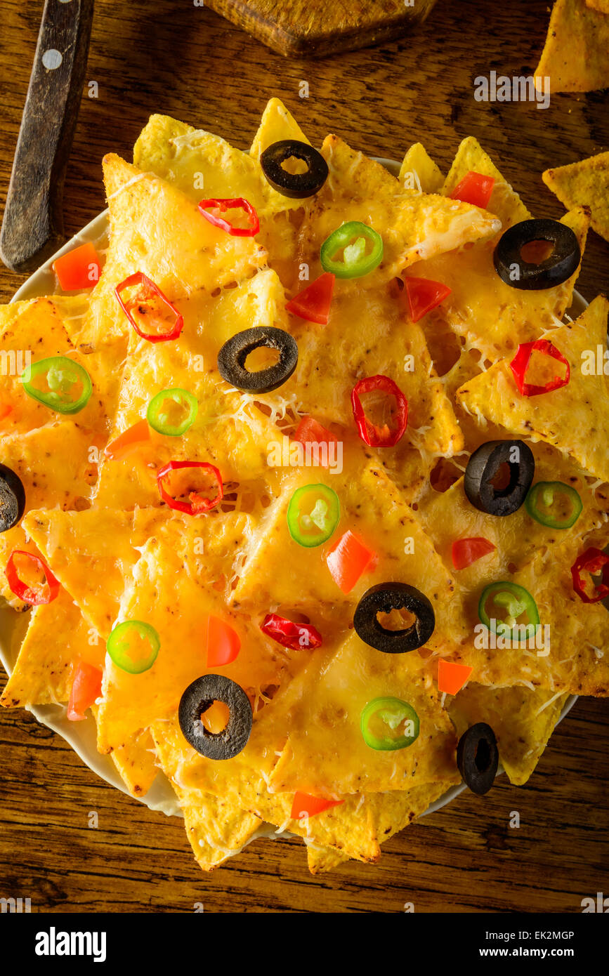Closeup nachos con queso, aceitunas y chiles en una placa Foto de stock