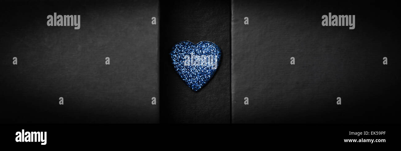 Cerca de una caja negra con un corazón azul. Los laterales de la caja tiene un montón de espacio para copiar. Foto de stock