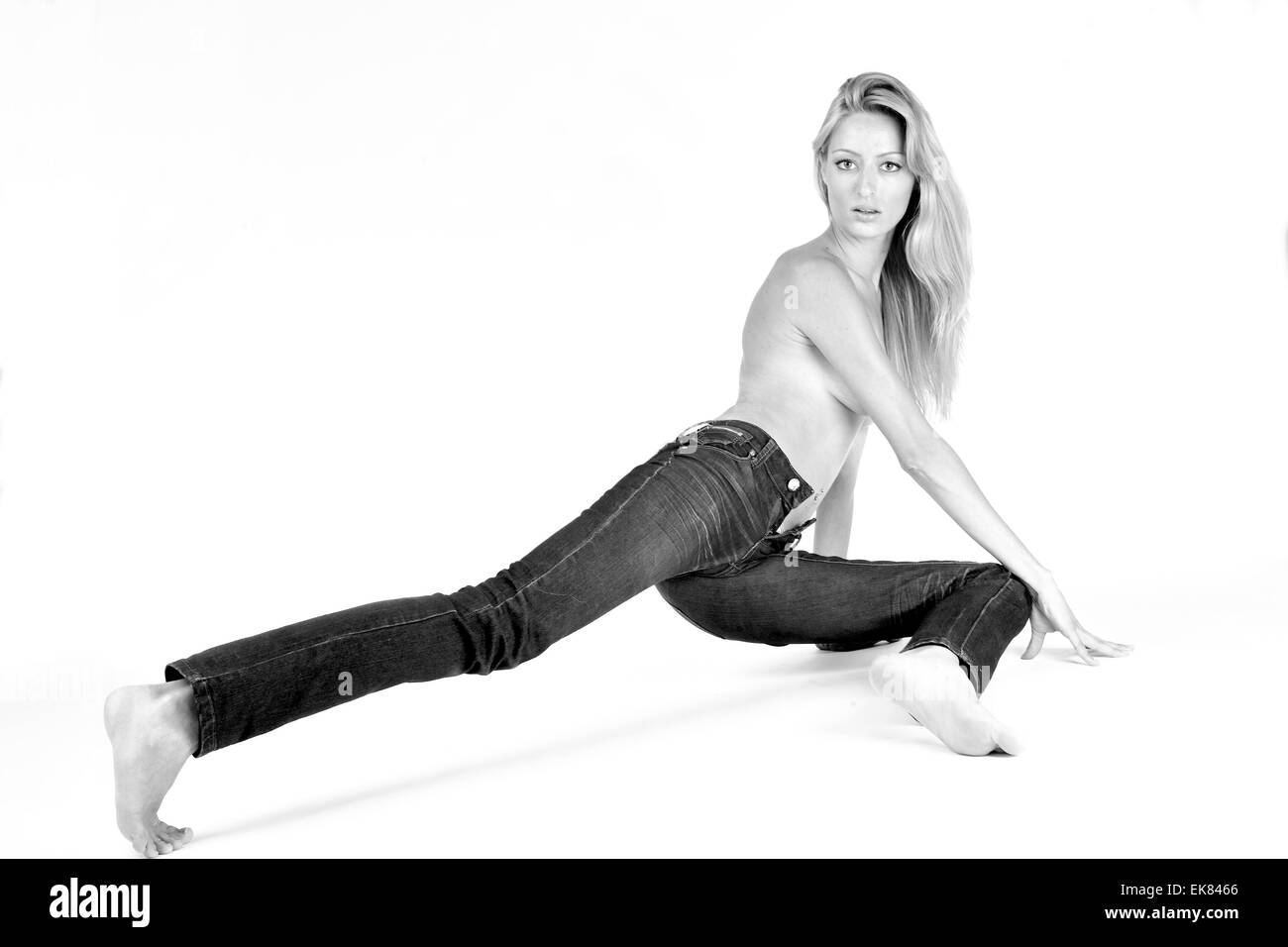 Retrato de una joven en jeans estirando su pierna Foto de stock